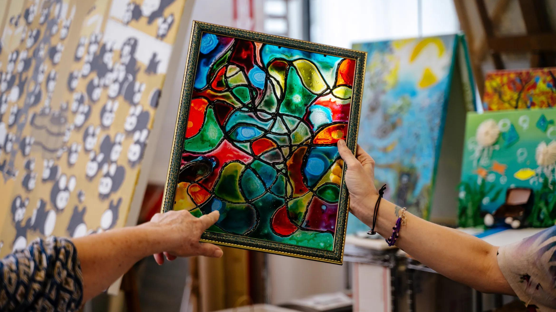 A patient holds up a stained glass art project made during art therapy at The Art Experience in Pontiac, Michigan.